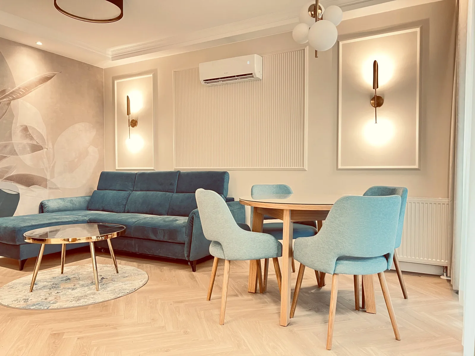Luksusowy apartament pomiędzy Stocznią a morzem — okrągły stół jadalniany z pastelowoniebieskimi krzesłami przy sofie