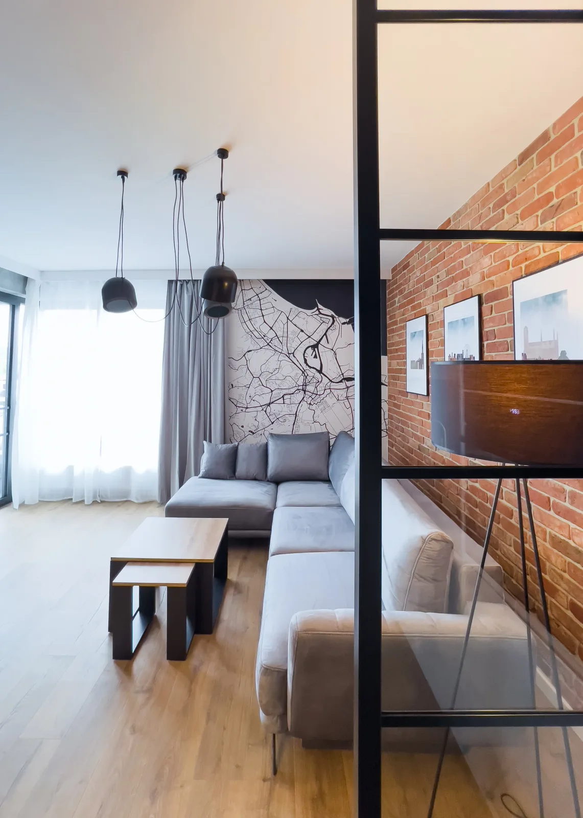 Apartament na DOKI 22F — salon widziany przez szklaną ścianę działową, przy oknie od podłogi do sufitu